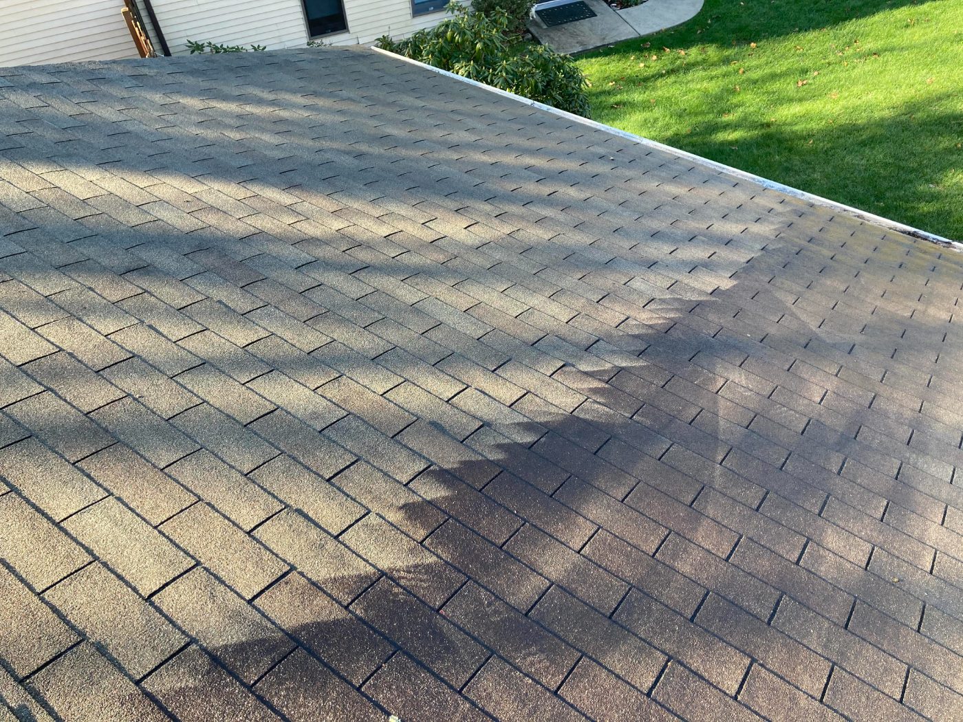 Newly installed asphalt shingle roof with gray and tan colored shingles in diagonal pattern